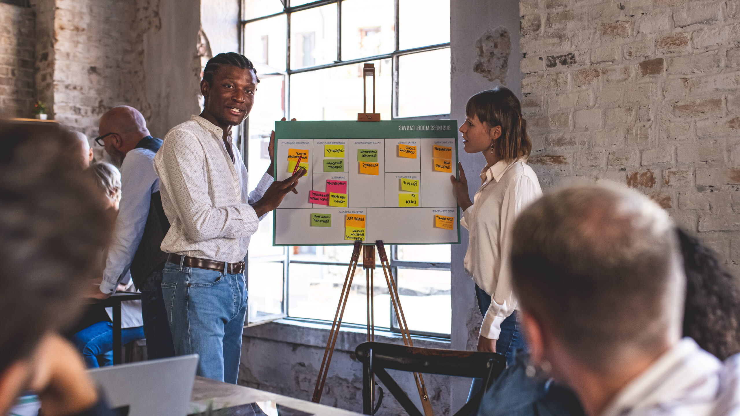 Mixed age range business people working in office, creatives and designers working on new project, startup concept, young African American man explaining strategy.